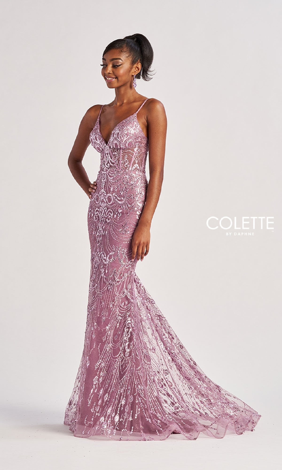 A woman wears the Colette CL8630 long prom dress, a fitted floor-length mauve sequin gown with thin straps, V-neckline, strappy open back, intricate patterns, and a slight train—posing against a plain background.